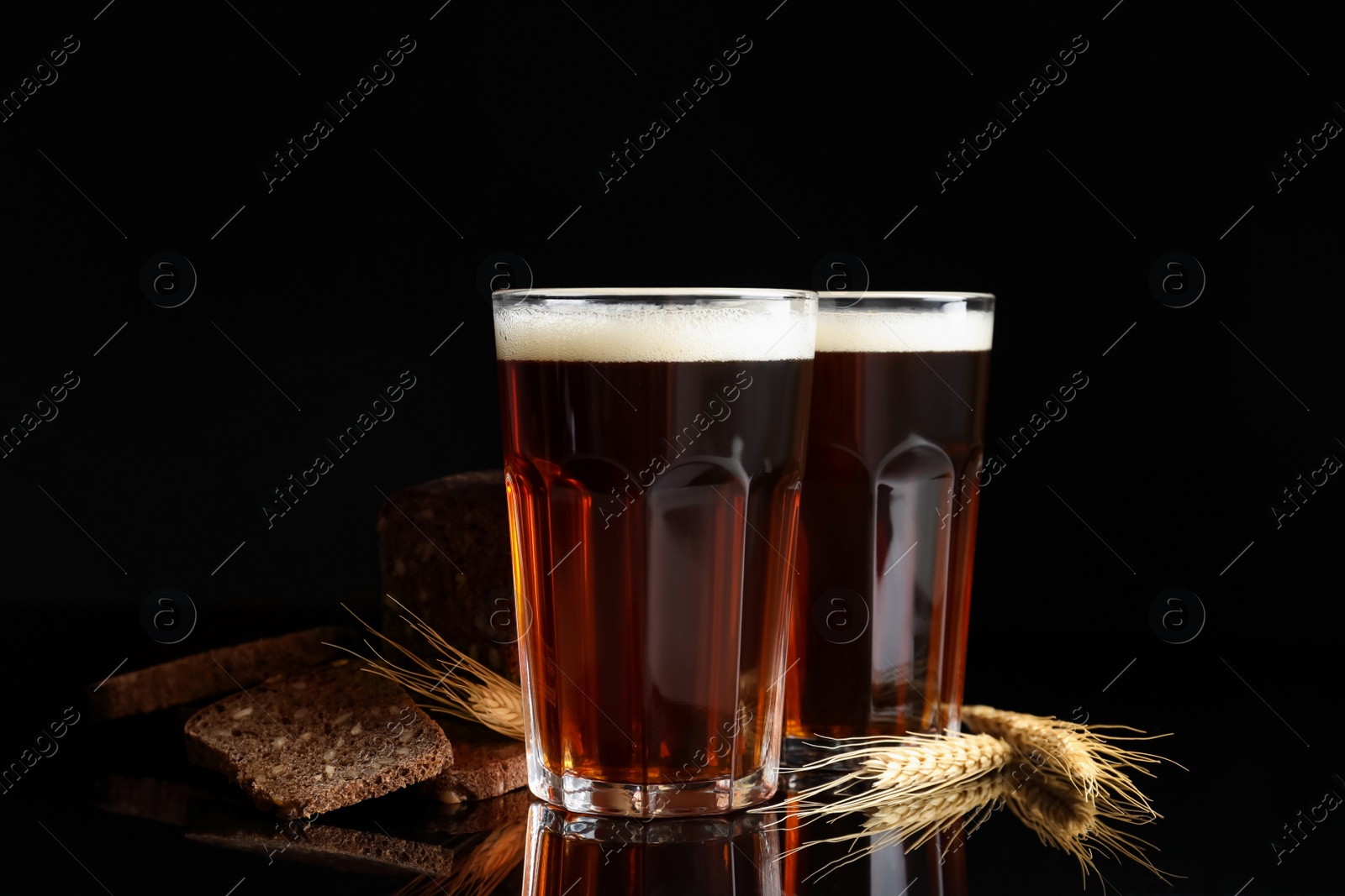 Photo of Delicious kvass, bread and spikes on black background