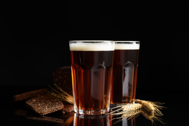 Photo of Delicious kvass, bread and spikes on black background