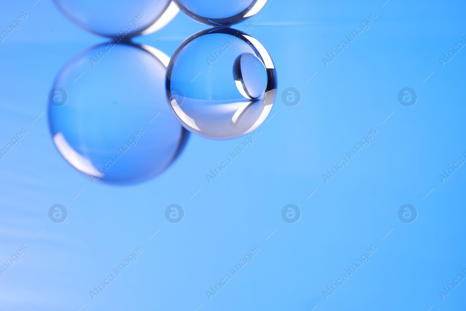 Photo of Transparent glass balls on blue background. Space for text