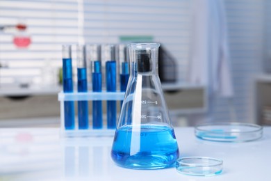 Photo of Laboratory analysis. Different glassware with blue liquid on white table indoors