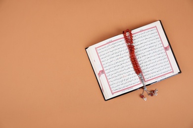 Photo of Muslim prayer beads, Quran and space for text on color background, top view