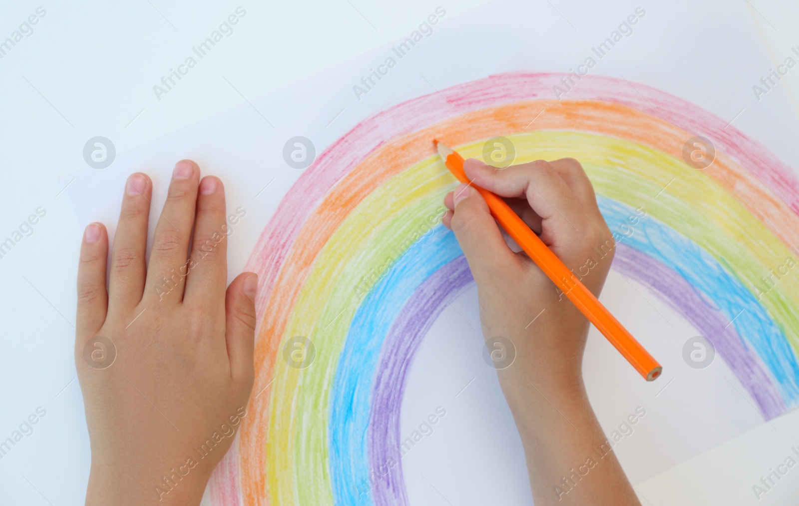 Photo of Little child drawing rainbow on white background, top view. Stay at home concept