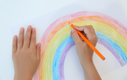 Little child drawing rainbow on white background, top view. Stay at home concept