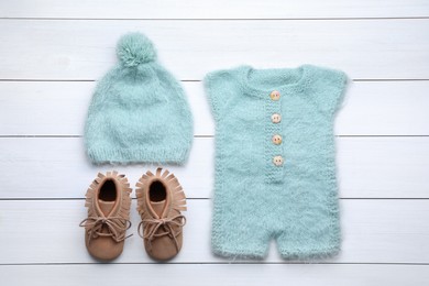 Photo of Flat lay composition with child's clothes and booties on white wooden table