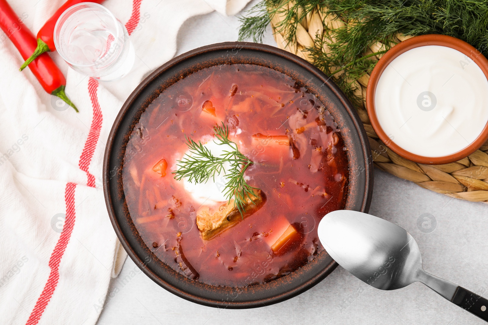 Photo of Tasty borscht with sour cream in bowl served on grey table, flat lay