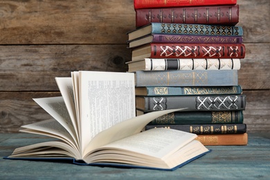 Photo of Hardcover books on light blue table against wooden background