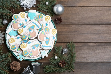 Tasty gingerbread cookies and festive decor on wooden table, flat lay with space for text. St. Nicholas Day celebration