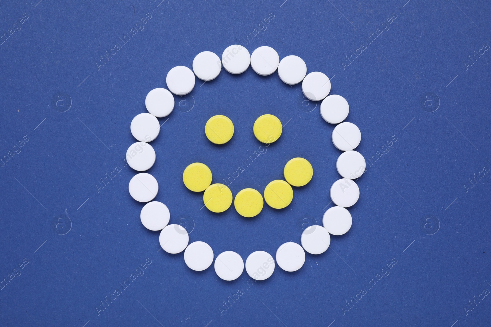 Photo of Happy face made of antidepressant pills on dark blue background, flat lay