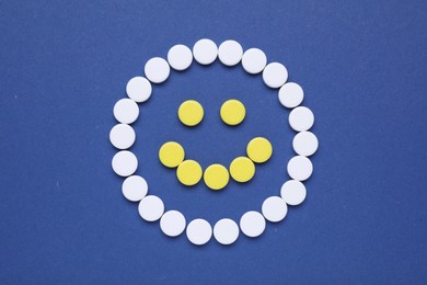 Photo of Happy face made of antidepressant pills on dark blue background, flat lay