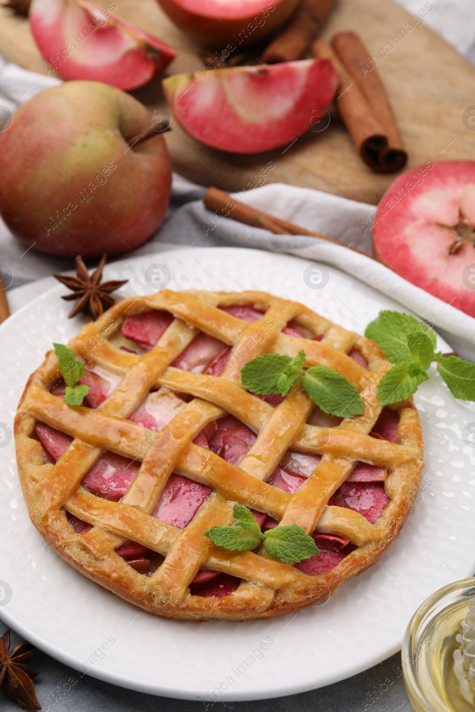 Photo of Delicious apple pie with mint and ingredients on table