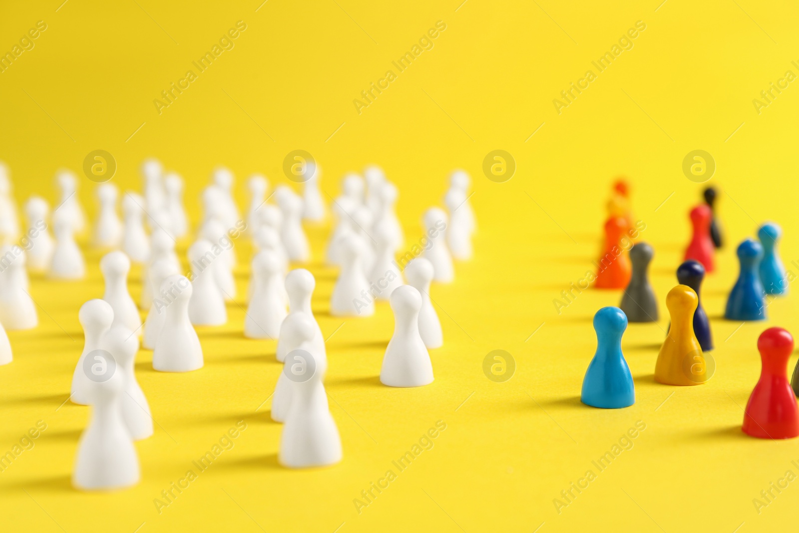 Photo of Colorful pawns on yellow background. Social inclusion concept