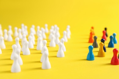 Colorful pawns on yellow background. Social inclusion concept