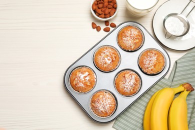 Flat lay composition with homemade banana muffins and milk on white wooden table. Space for text