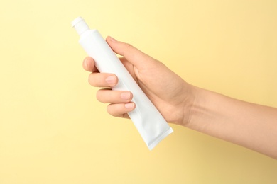 Photo of Woman holding tube with toothpaste against color background. Dental care