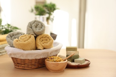 Photo of Dry flowers, soap bars and towels on wooden table indoors, space for text. Spa time