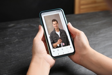 Image of Woman visiting dating site via smartphone at table, closeup