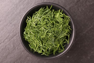 Fresh cut dill in bowl on dark table, top view