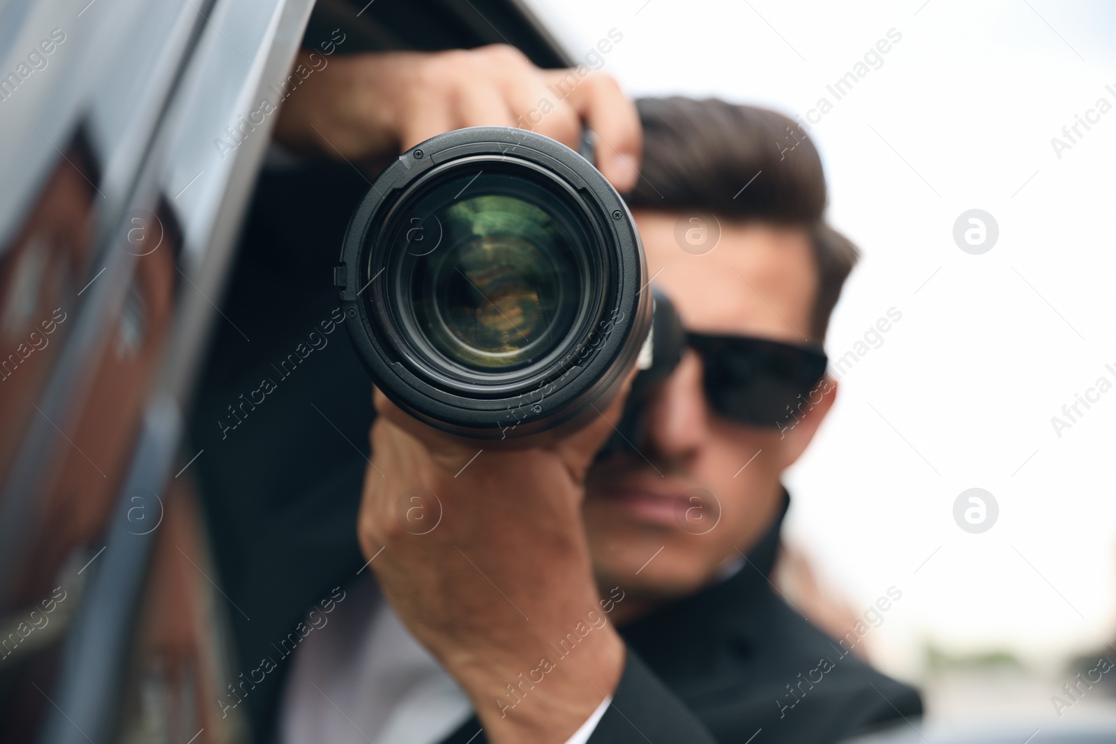 Photo of Private detective with camera spying from car, focus on lens