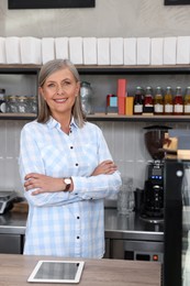 Photo of Portrait of happy business owner at cashier desk in her coffee shop