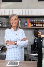 Portrait of happy business owner at cashier desk in her coffee shop