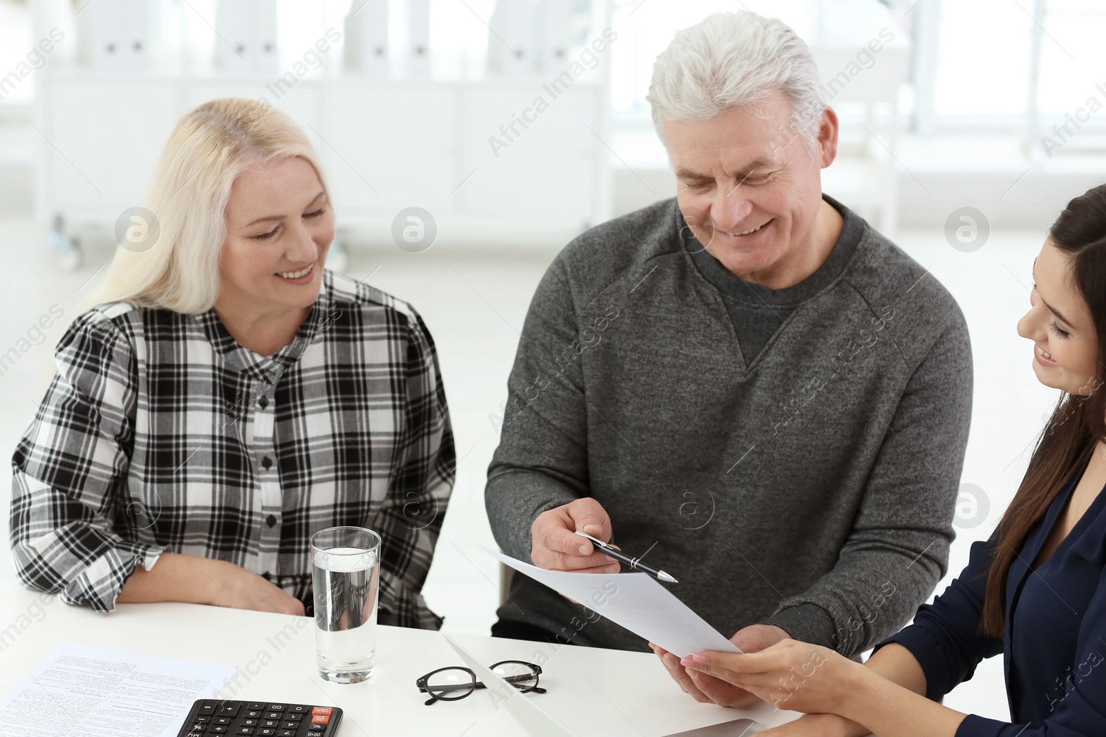 Photo of Mature couple discussing pension with consultant in office