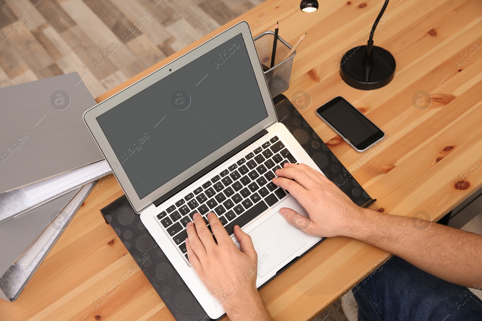 Photo of Young man using modern laptop at table, closeup