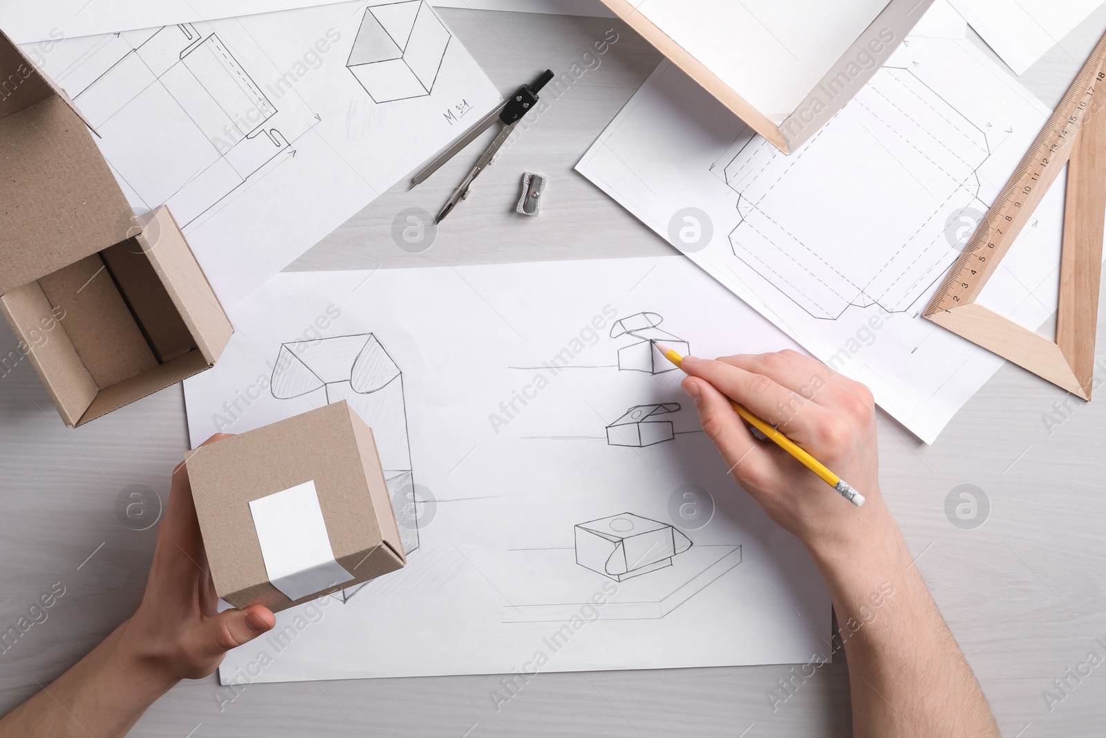 Photo of Man creating packaging design at light wooden table, top view