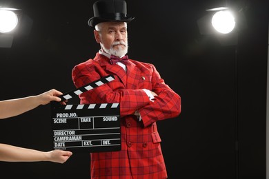 Senior actor performing role while second assistant camera holding clapperboard on stage. Film industry