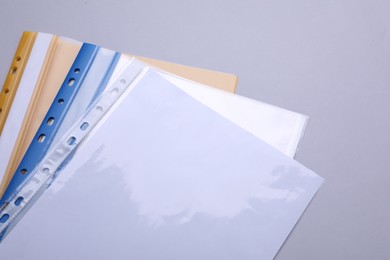 Photo of File folders with punched pockets and paper sheets on light grey background, above view