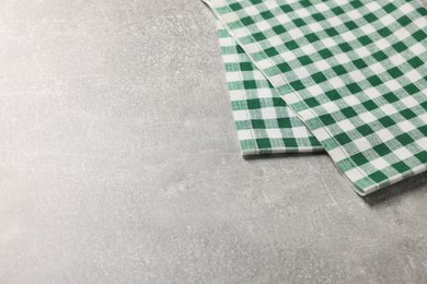 Photo of Green checkered tablecloth on light gray textured table, space for text