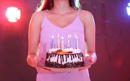 Photo of Young woman with birthday cake in nightclub, closeup