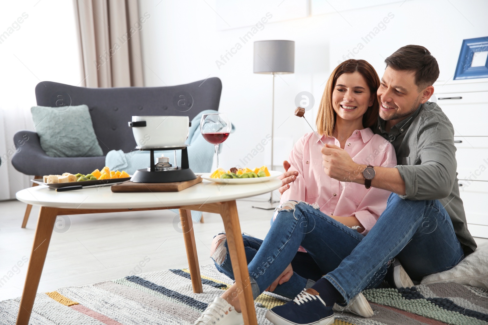 Photo of Happy couple enjoying fondue dinner at home