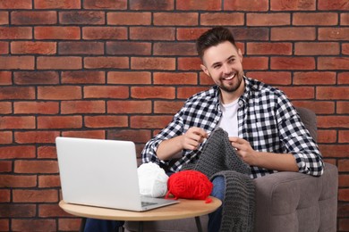 Photo of Man learning to knit with online course at home. Time for hobby