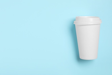 Photo of Takeaway paper coffee cup with on light blue background, top view. Space for text