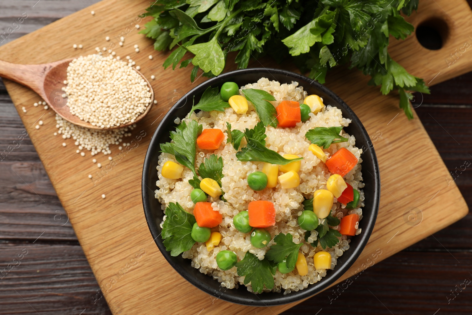 Photo of Tasty quinoa porridge with vegetables in bowl on wooden table, flat lay