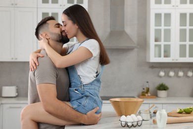 Affectionate young couple kissing in kitchen. Space for text