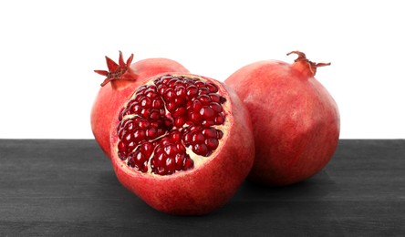 Photo of Fresh pomegranates on black wooden table against white background