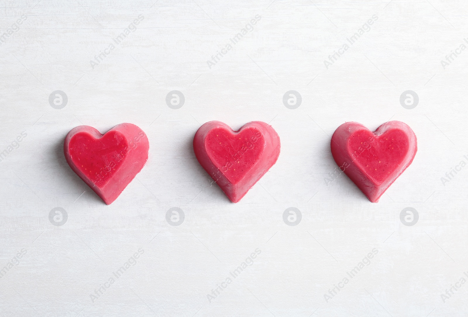 Photo of Heart shaped berry ice cubes on light background, flat lay