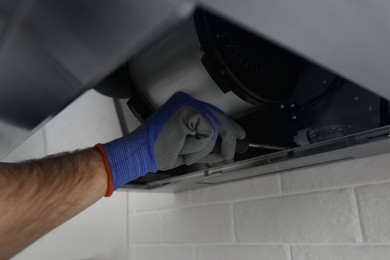 Photo of Worker repairing modern cooker hood indoors, closeup