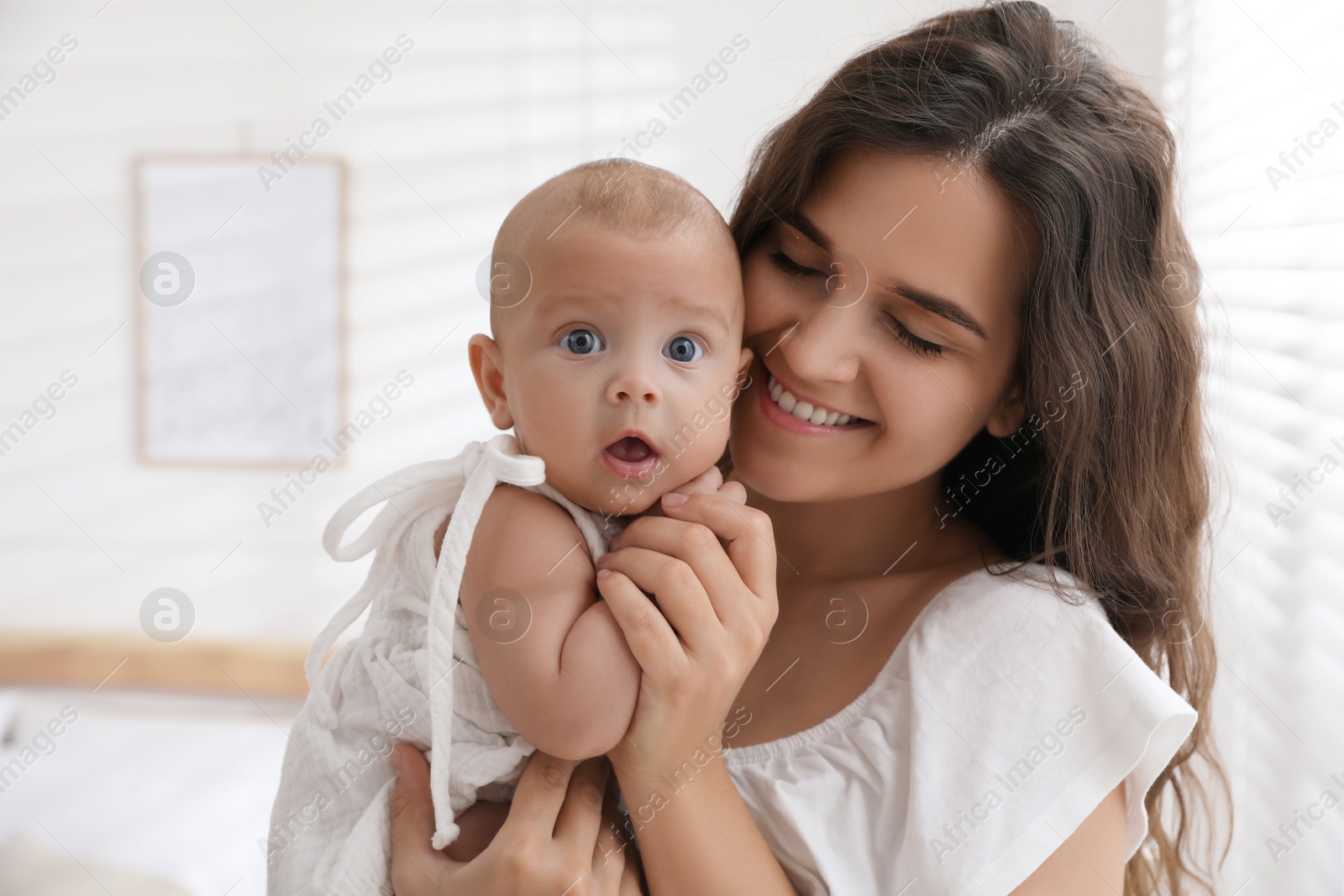 Photo of Happy young mother with her cute baby near window at home