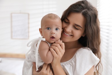 Happy young mother with her cute baby near window at home