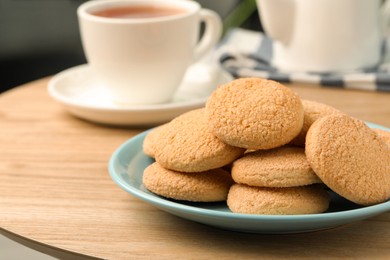 Photo of Delicious sugar cookies and tea on wooden table, closeup. Space for text