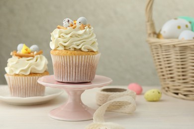 Photo of Tasty Easter cupcakes with vanilla cream on light wooden table