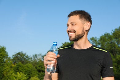 Photo of Happy man with bottle of water on hot summer day. Refreshing drink