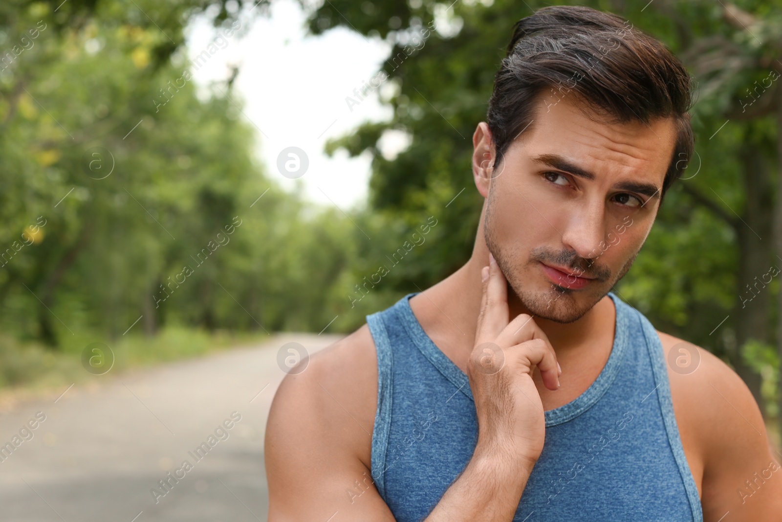 Photo of Young man checking pulse after training in park. Space for text