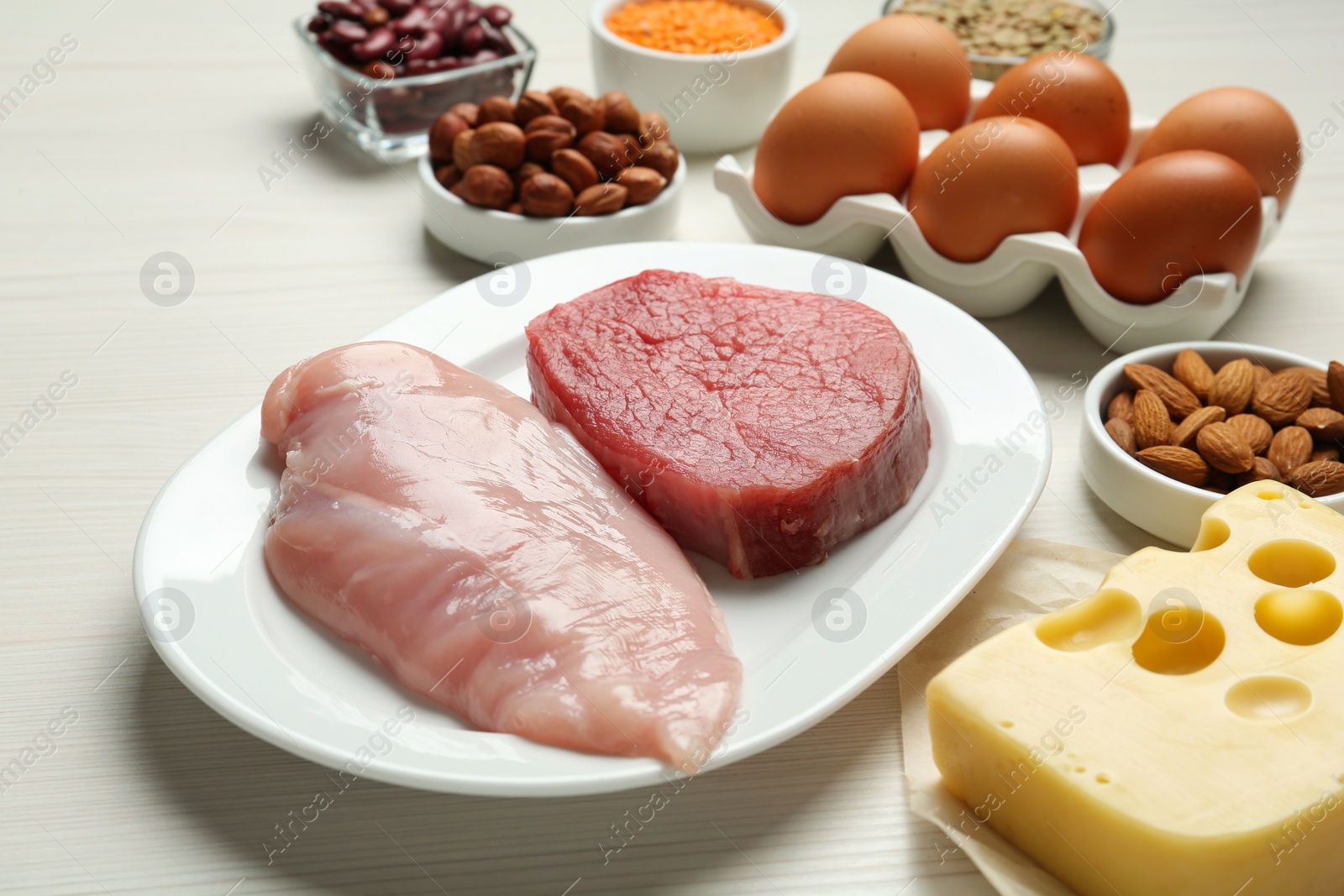 Photo of Fresh meat and other products on white wooden table, closeup. Sources of essential amino acids