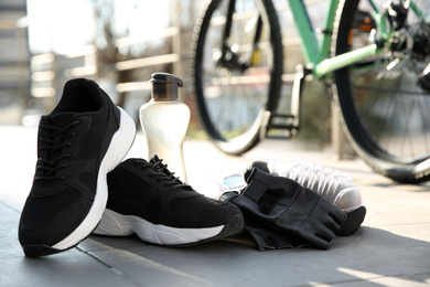Bicycle gloves, shoes and bottle outdoors on sunny day