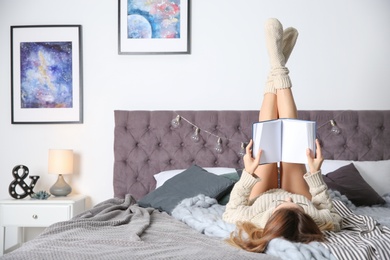 Photo of Young woman reading book on bed at home