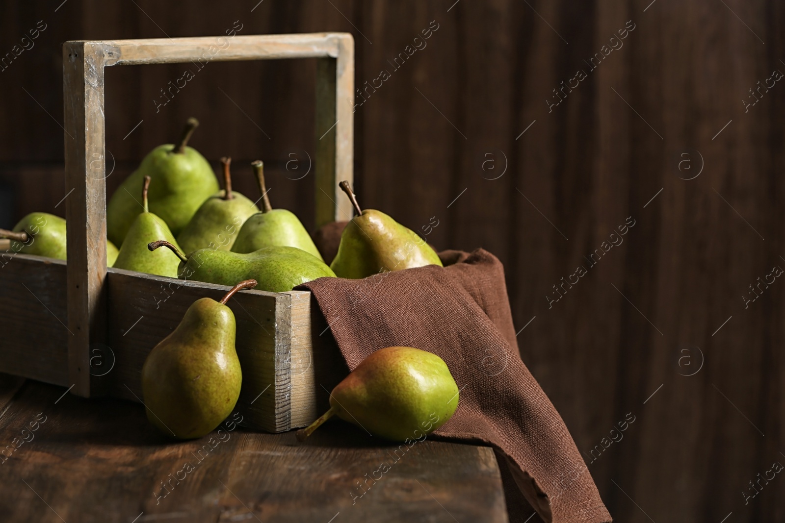 Photo of Basket with ripe pears on wooden table. Space for text