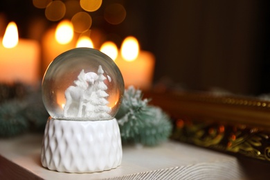 Snow globe on wooden table against blurred background, space for text. Bokeh effect